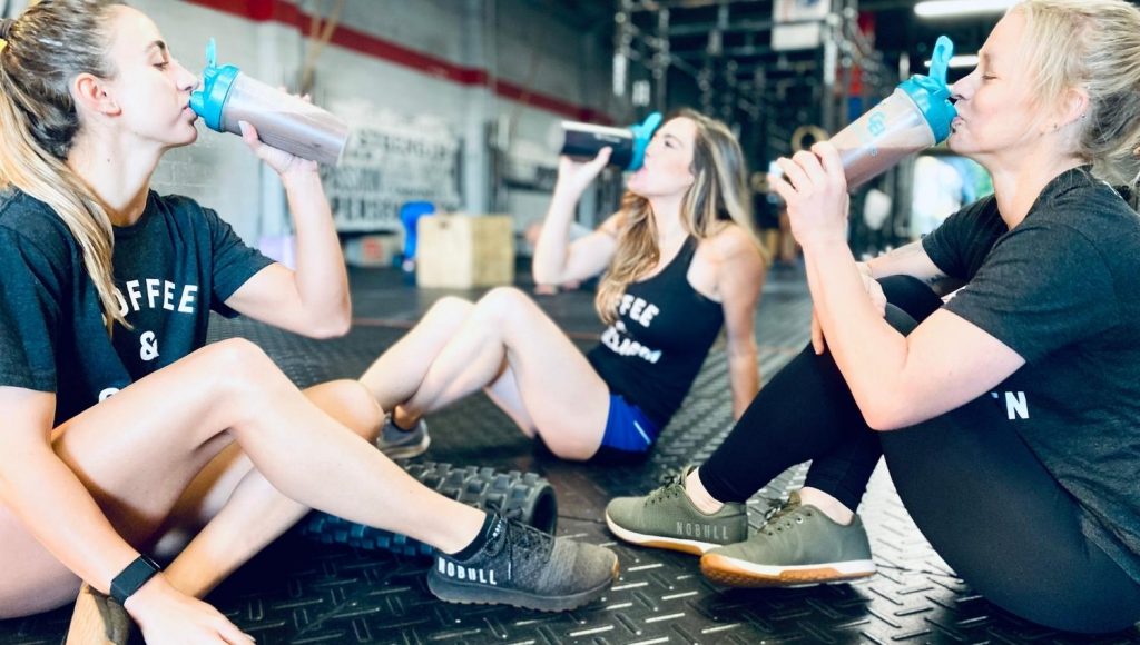 Girls at gym taking collagen in shaker bottles